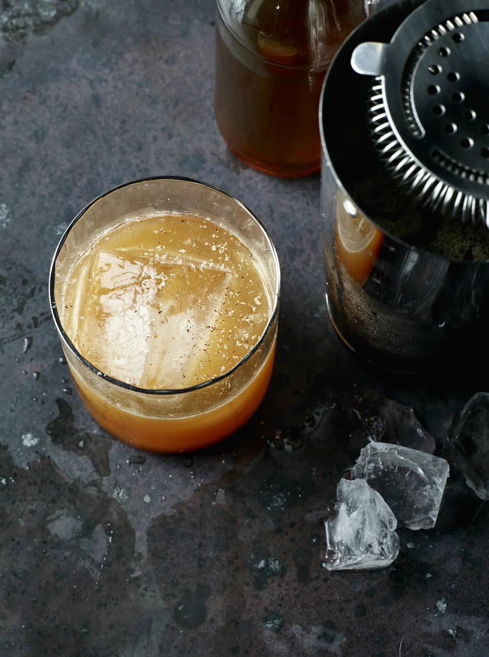 A craft cocktail with smoky bar shaker and ice